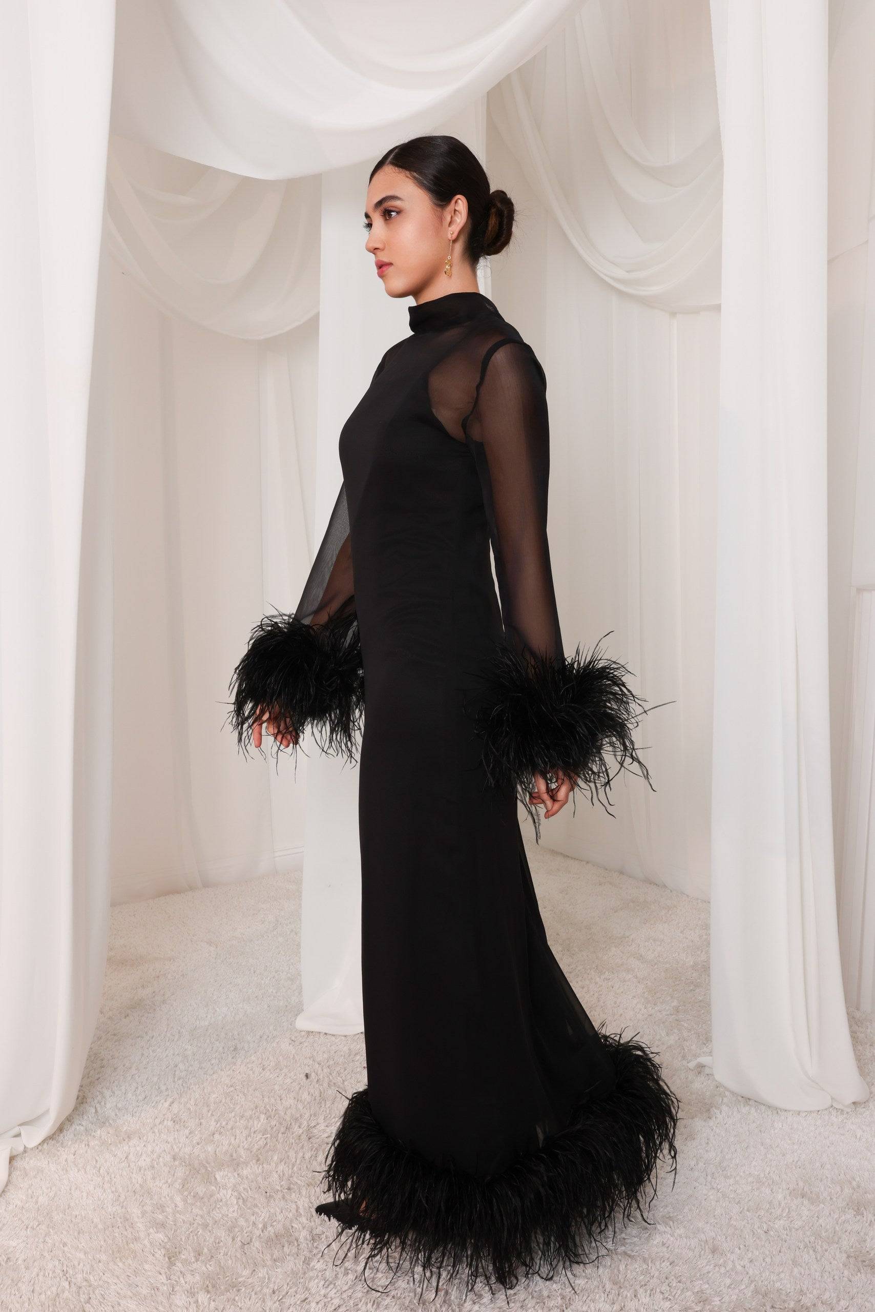Side view of the Leila black evening gown featuring a high neckline, sheer sleeves, and ostrich feather details. A sophisticated silhouette for formal occasions.