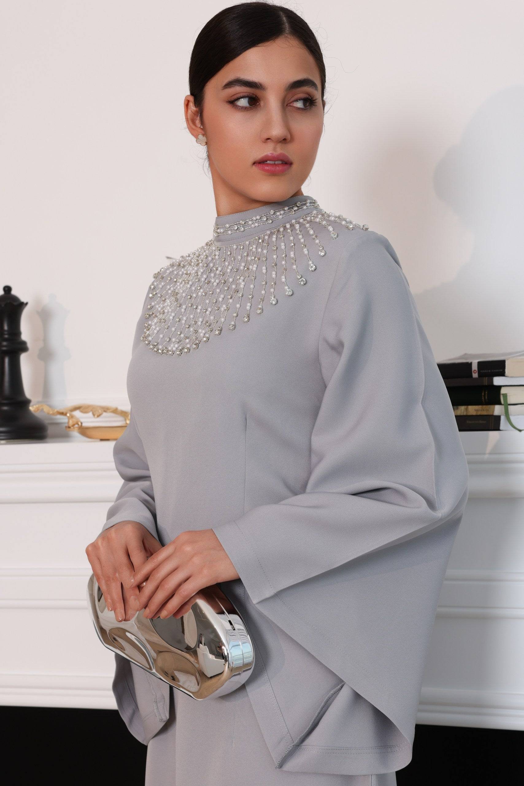 Close-up of the Durrah elegant dress, showcasing its pearl-embellished high neckline and flowing sleeves. A perfect blend of sophistication and modern style.