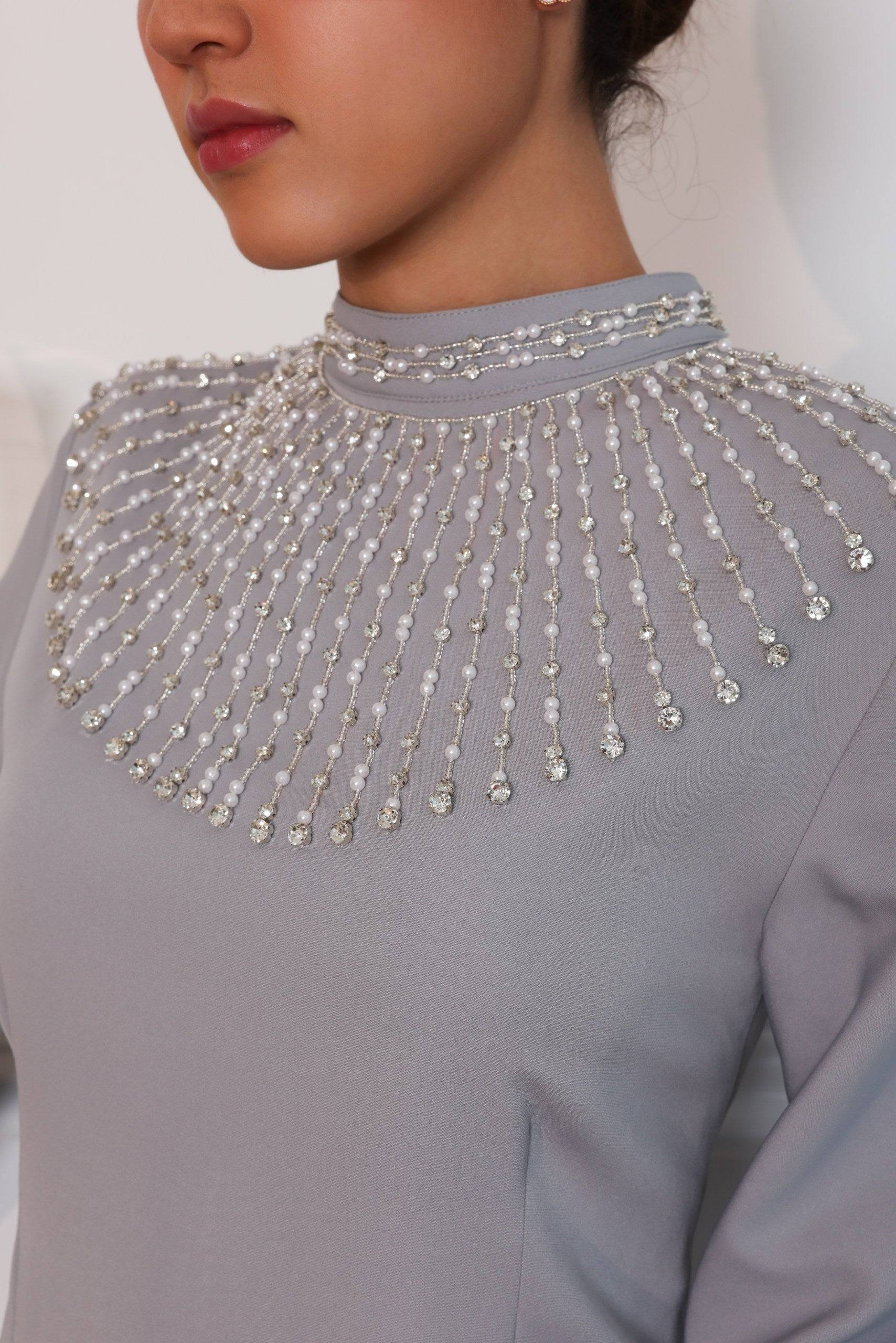 Detailed view of the Durrah dress's pearl-embellished high neckline. The intricate design adds a touch of luxury to this timeless, tailored-fit piece.